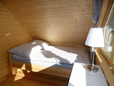 Zdjęcie przedstawia łóżko w pokoju - DOMKI DREWNIANE CAŁOROCZNE – „CZTERY PORY ROKU” | Trzęsacz (wypoczywaj nad morzem) 