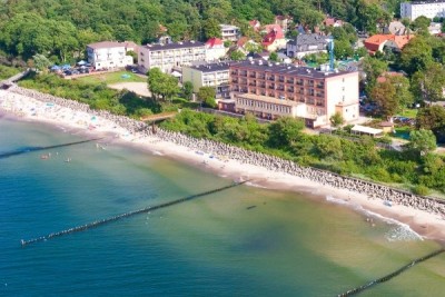 Fotografia wykonana z perspektywy lotu ptaka nad morzem, prezentująca hotel Hotel *** Wodnik SPA w Ustroniu Morskim.